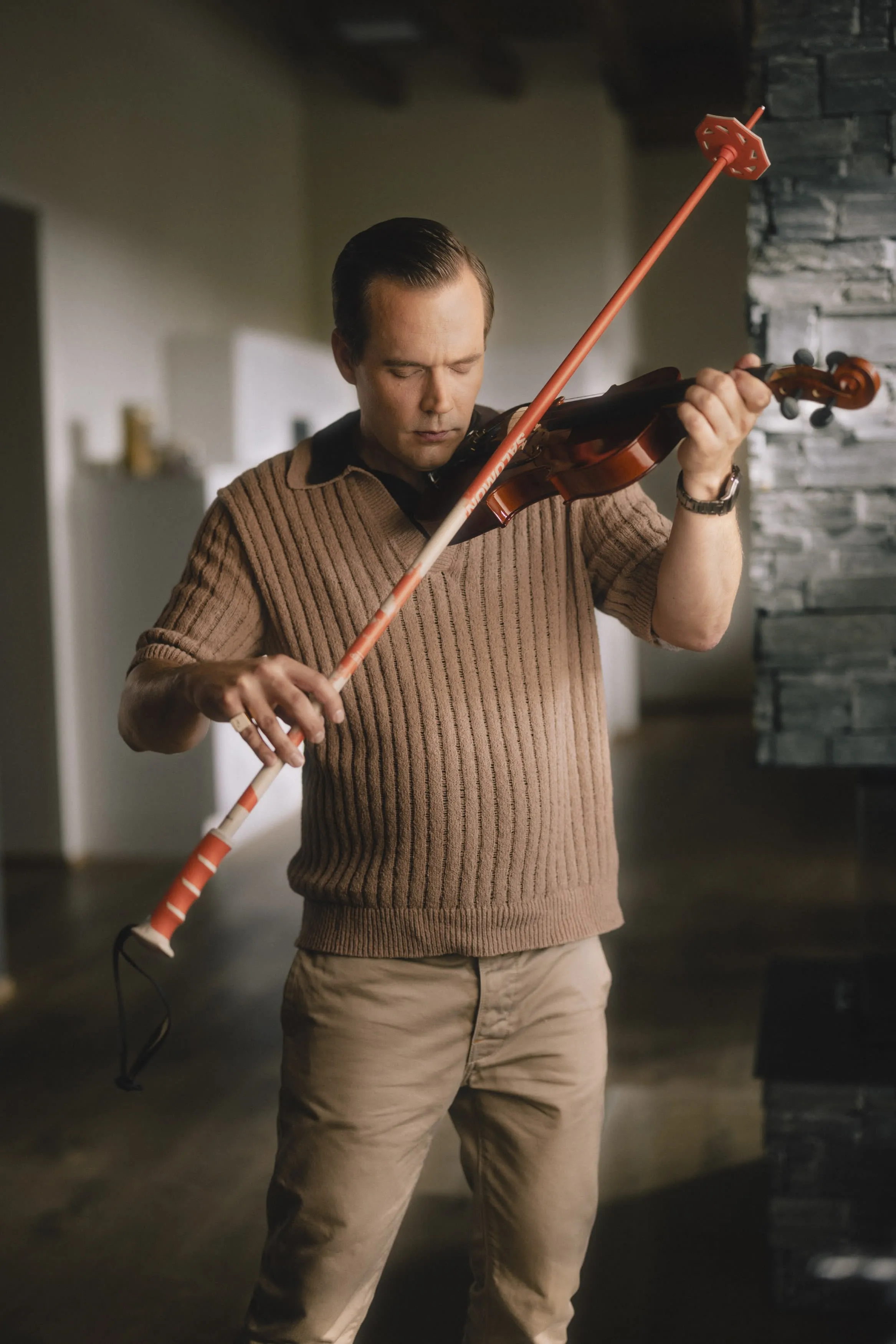 Ein Mann spielt Violine mit dem Skistock