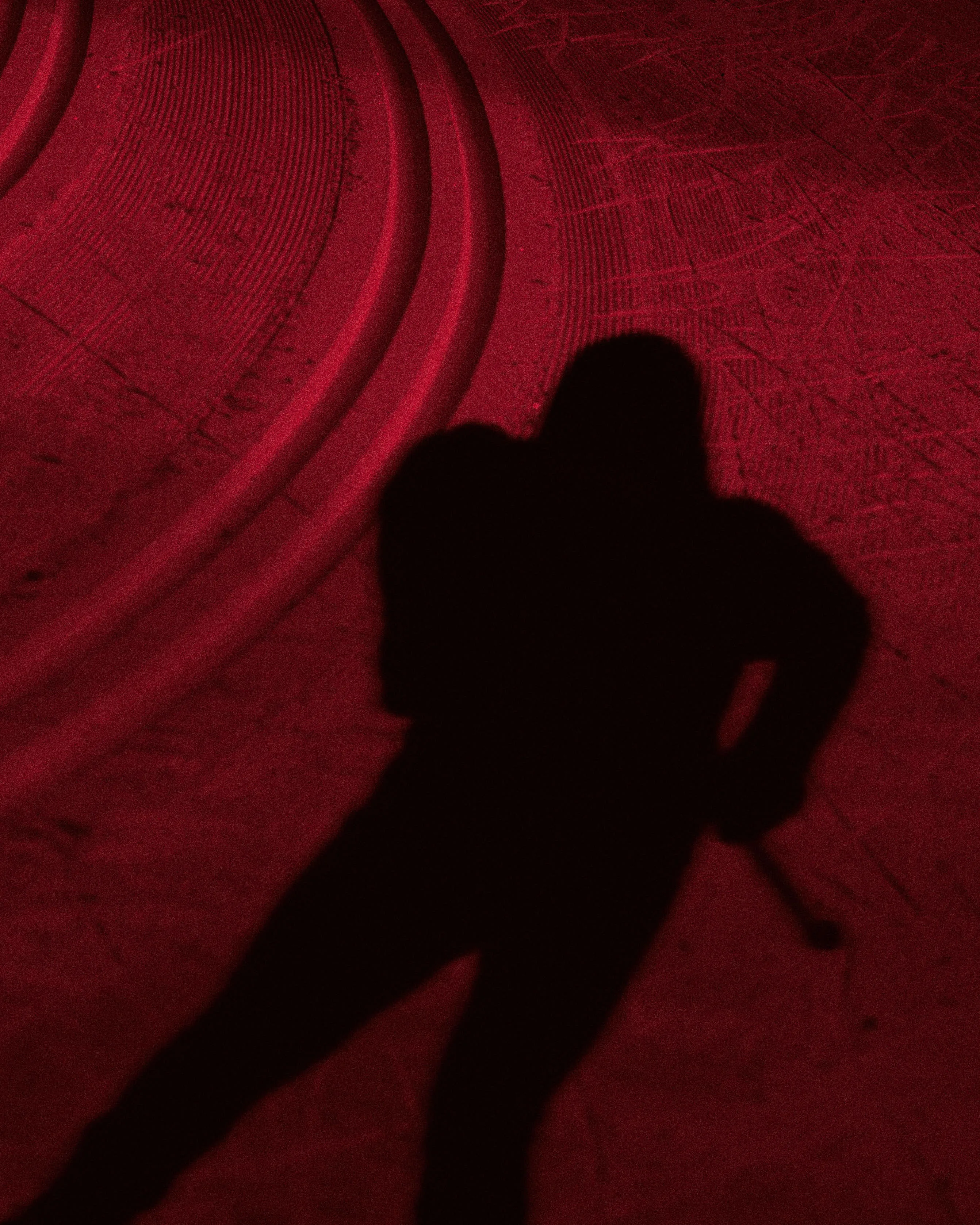 Abstract silhouette of a Cross country skier cast on snow under red light.
